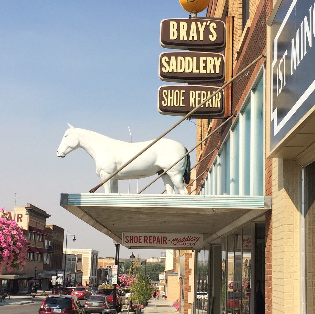 Picture of the outside of Bray's Saddlery with the white horse that has been outside of the store close to 50 years